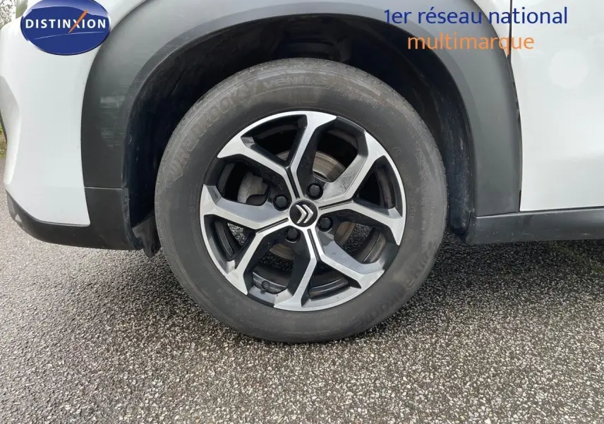 Gros plan sur la roue avant gauche d'une Citroën C3 Aircross blanc polaire avec jante alliage distinctive.