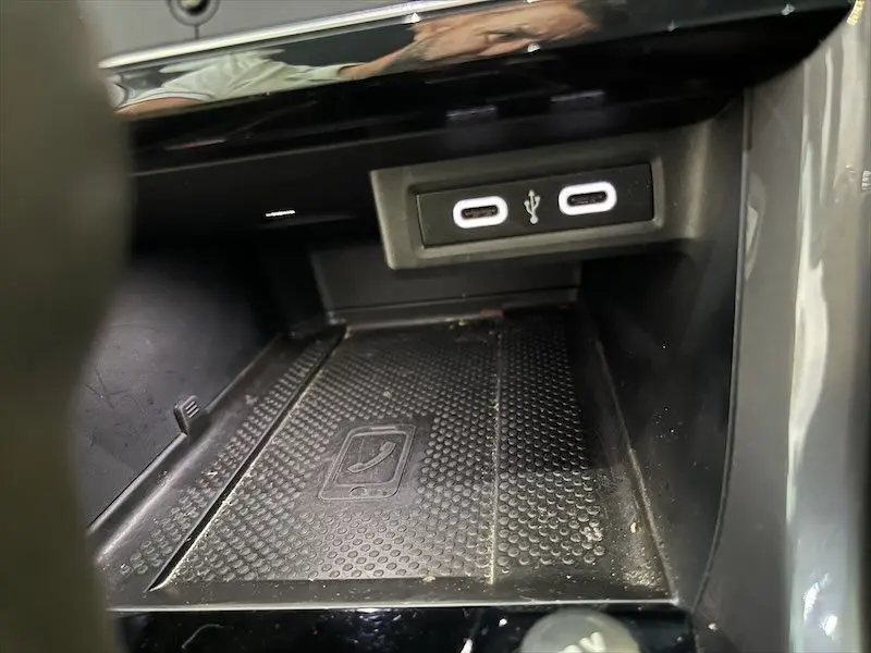 Gros plan sur la console centrale du Volkswagen T-Cross gris, montrant les ports USB et un espace de rangement avec tapis antidérapant.