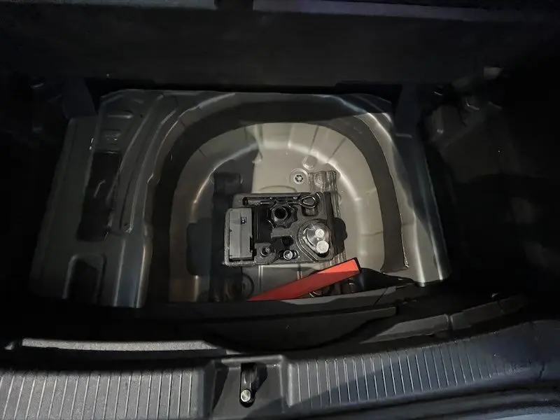 Coffre ouvert d'un Volkswagen T-Cross gris Limestone, montrant le compartiment de rangement sous le plancher arrière.