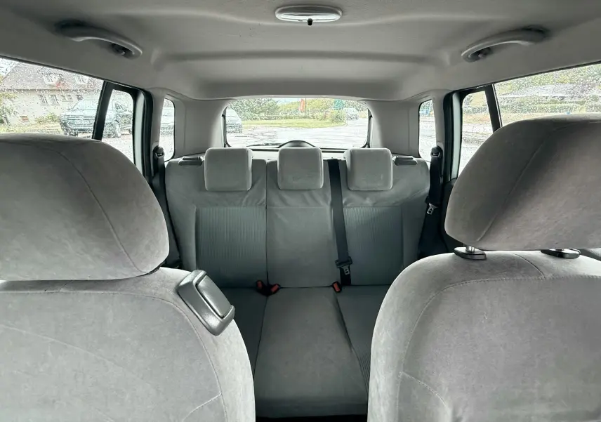 Vue intérieure arrière montrant les sièges gris clair d'une Ford Fusion 2002, avec trois appuie-têtes et ceinture centrale.