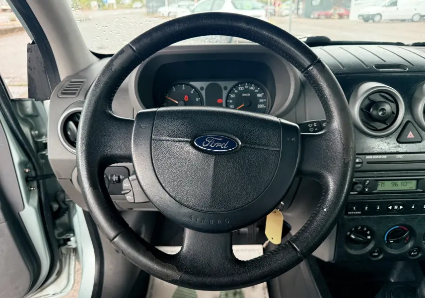 Vue centrée sur le volant en cuir noir d'une Ford Fusion 2002, avec tableau de bord et commandes visibles.
