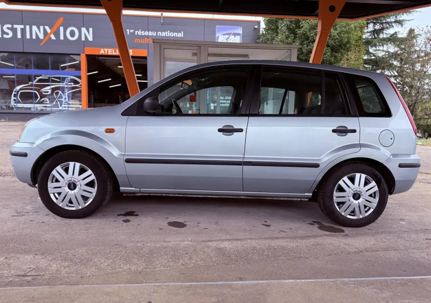 Profil côté gauche d'une Ford Fusion bleu clair de 2002, compacte avec cinq portes et jantes acier à enjoliveurs blancs.