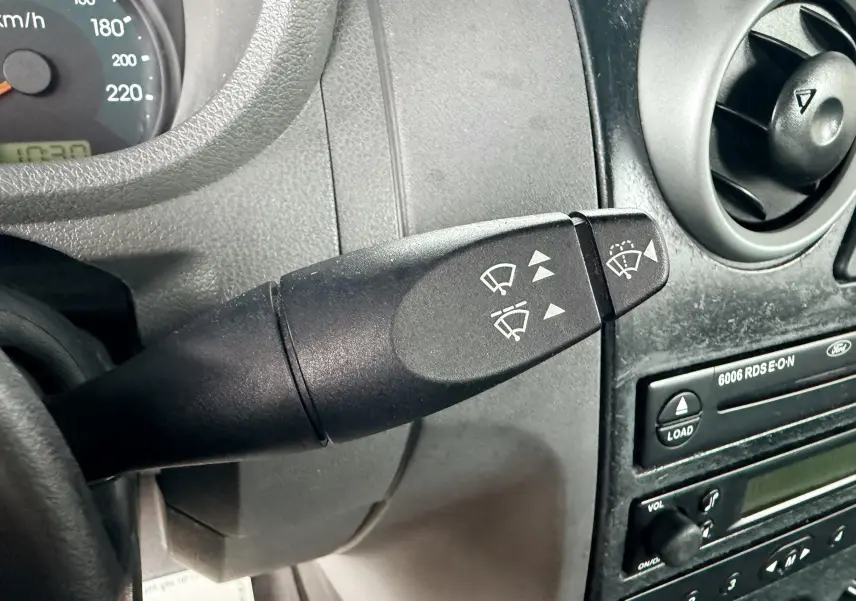 Gros plan sur la manette d'essuie-glace à gauche du volant dans l'habitacle gris d'une Ford Fusion 2002.