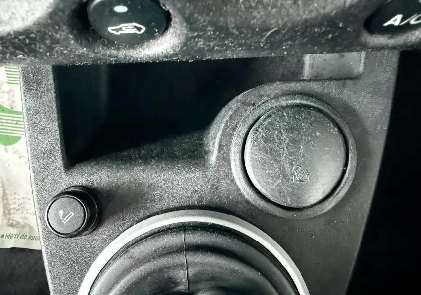 Gros plan sur la console centrale noire de la Ford Fusion 2002, montrant les prises allume-cigare et cendrier.