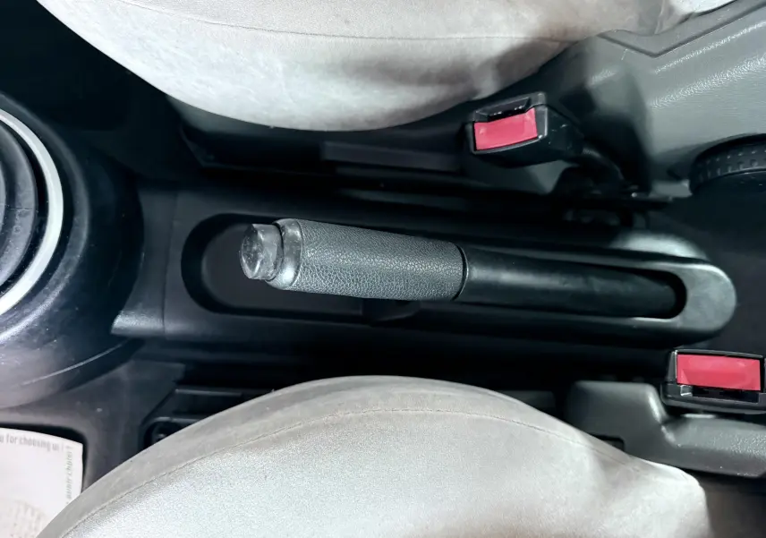 Vue rapprochée de la poignée de frein à main et des ceintures grises entre les sièges avant d'une Ford Fusion bleu clair.