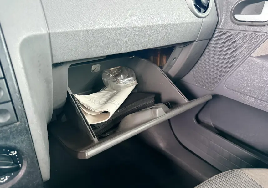 Gant de boîte à gants ouvert côté passager avec documents et lampe dans une Ford Fusion 2002 gris intérieur.