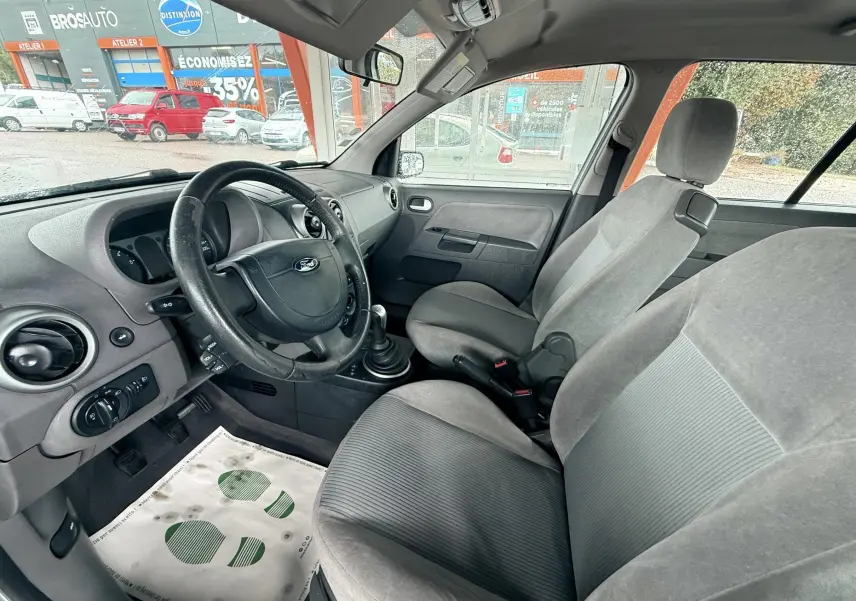 Intérieur avant d'une Ford Fusion 2002, sièges gris et volant cuir, vue côté conducteur avec tableau de bord simple.