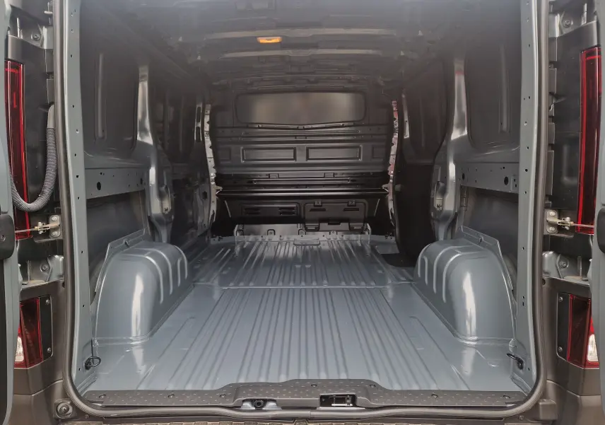 Vue intérieure arrière du fourgon Renault Trafic L1H1 gris urbain, montrant l'espace de chargement vide et métallique.