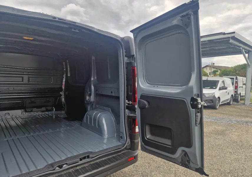 Vue arrière ouverte du Renault Trafic Fourgon gris urbain 2025, montrant l'espace de chargement vide et la porte battante droite déployée.