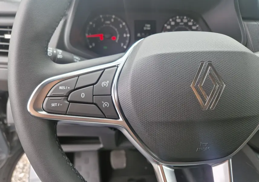 Gros plan sur le volant du Renault Trafic Fourgon gris urbain 2025, avec commandes intégrées et logo central brillant.