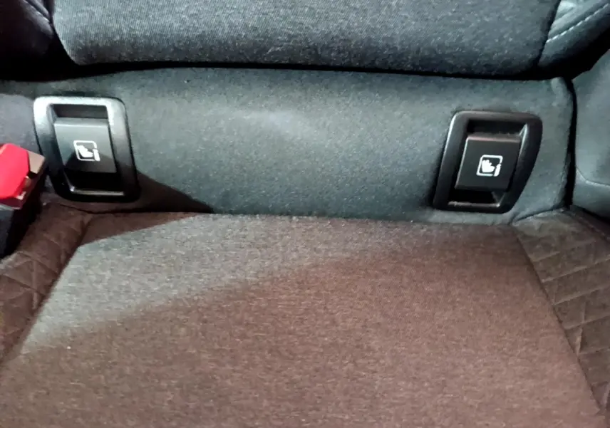 Détail des commandes de rabattement des sièges arrière sur la banquette tissu d'une Renault Clio Business blanche.