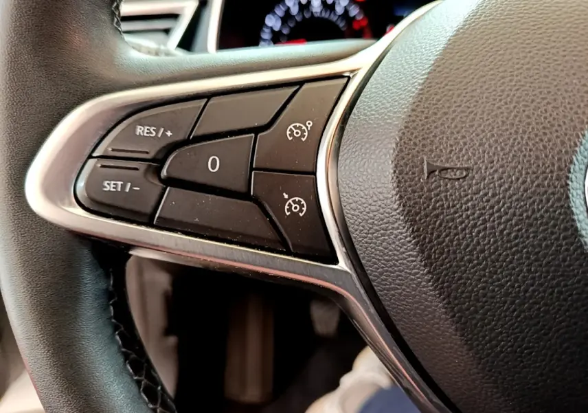 Gros plan sur les commandes du régulateur de vitesse au volant cuir noir de la Renault Clio Business blanche 2021.