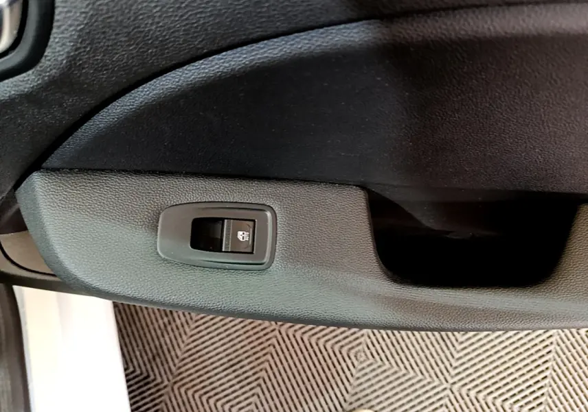 Bouton de commande de vitre sur la porte intérieure côté conducteur d'une Renault Clio blanche, vue rapprochée.