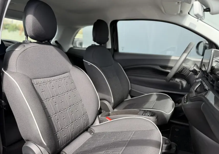Vue intérieure côté droit montrant les sièges avant en tissu noir avec surpiqûres blanches d'une FIAT 500 électrique 2024.