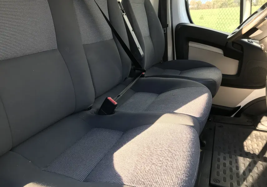 Intérieur du Peugeot Boxer 2014, vue côté gauche sur la banquette avant grise et le siège conducteur.