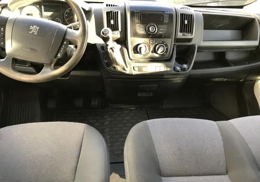 Vue intérieure frontale du tableau de bord du Peugeot Boxer Chassis Double Cabine 2014 avec volant, levier de vitesses manuel et sièges gris.