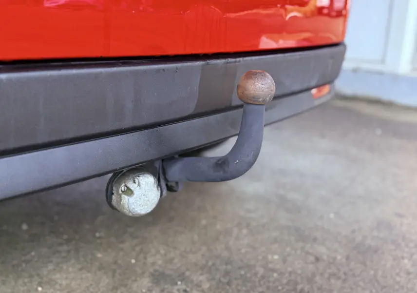 Gros plan sur l'attelage d'une FIAT Doblo Cargo rouge, avec pare-chocs arrière noir visible en arrière-plan.