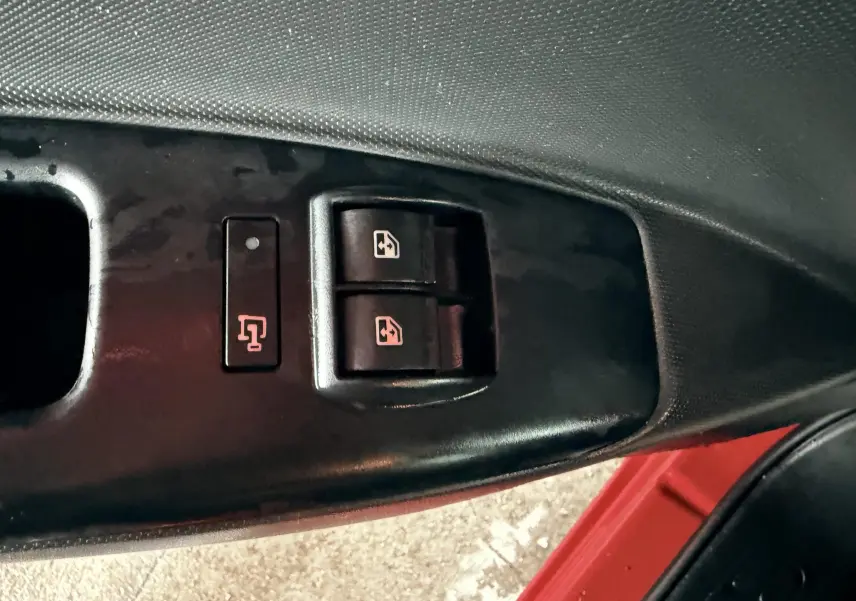 Gros plan sur les commandes des vitres électriques côté conducteur d’un Fiat Doblo Cargo rouge, intérieur noir.