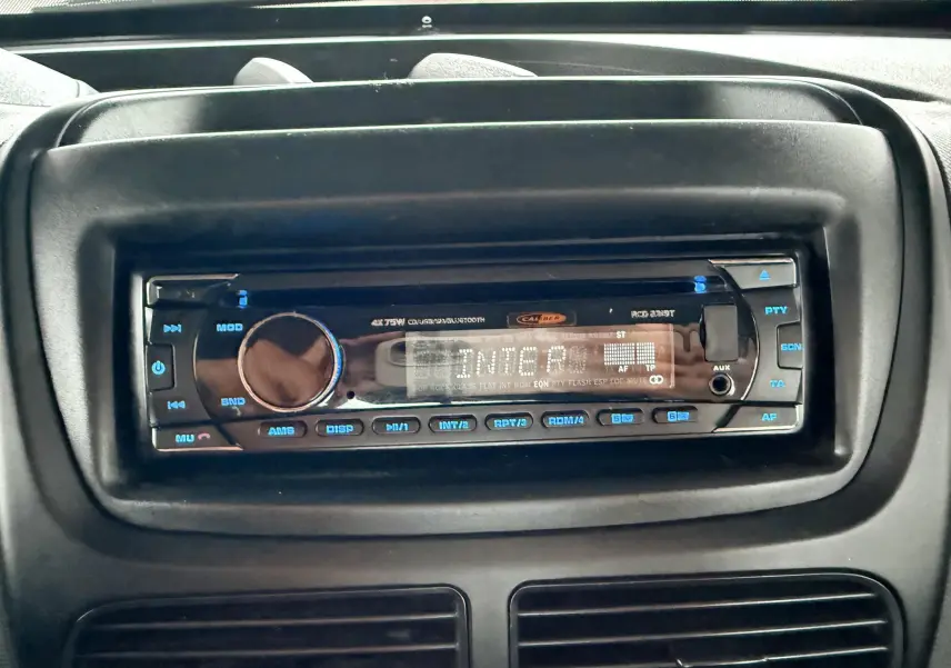 Gros plan sur la radio numérique intégrée au tableau de bord noir du Fiat Doblo Cargo rouge de 2011.