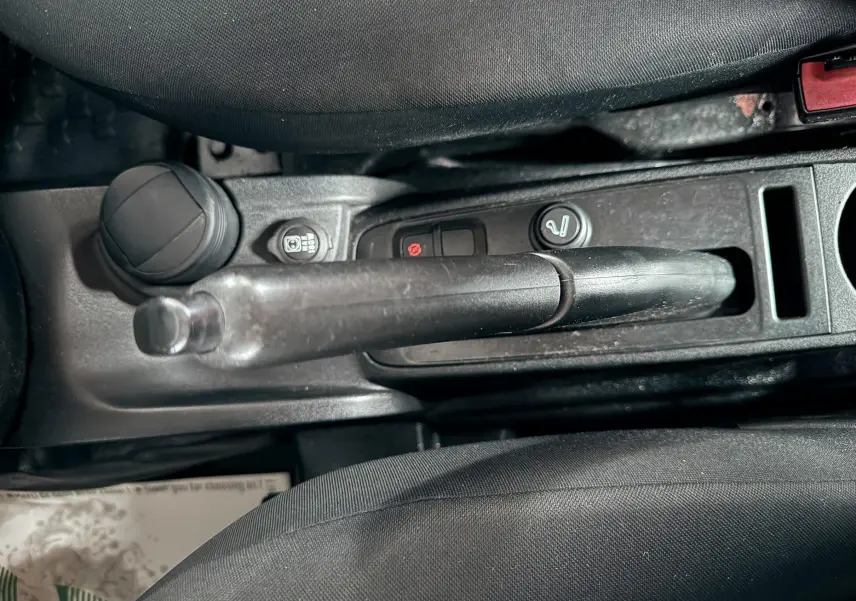 Vue rapprochée de la poignée de frein à main et console centrale noire du Fiat Doblo Cargo 2011.