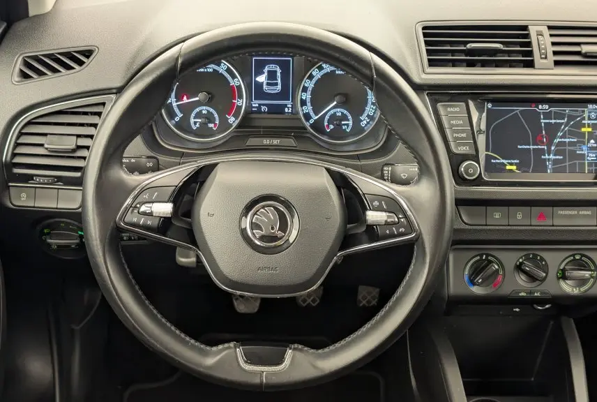 Vue intérieure centrée sur le volant et le tableau de bord de la Skoda Fabia Business 2020 avec écran de navigation allumé.