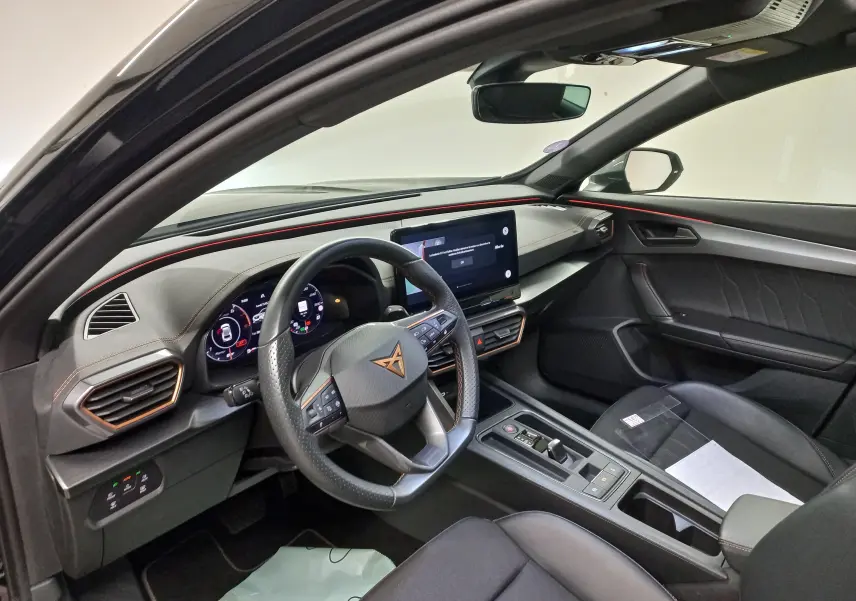 Intérieur du CUPRA Formentor 2023 vu côté conducteur, tableau de bord noir avec éclairage rouge et écran tactile central.