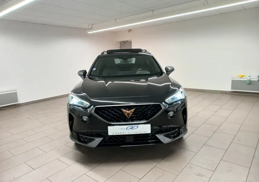Vue frontale d'un CUPRA Formentor 1.5 TSI 150 DSG7 VZ-LINE noir minuit avec phares LED allumés en intérieur.