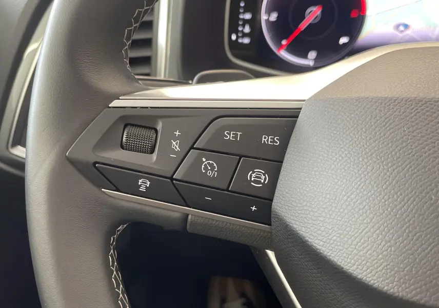 Gros plan sur les commandes au volant côté gauche du SEAT Ateca 2.0 TDI 150 DSG7 blanc Nevada 2024.