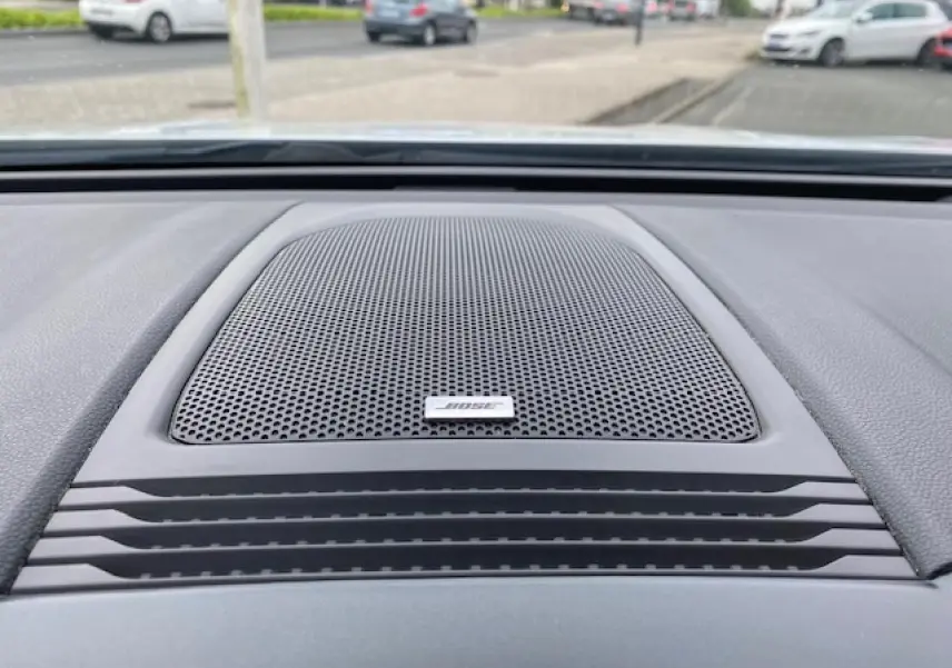 Gros plan sur l'enceinte Bose intégrée au tableau de bord du Renault Koleos blanc 2019, version Initiale Paris.