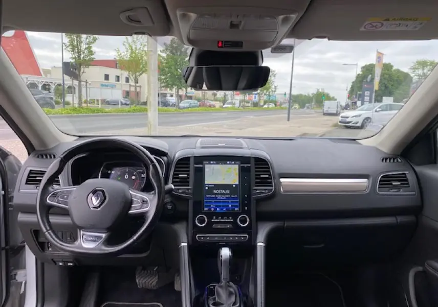 Vue intérieure frontale du tableau de bord noir du Renault Koleos blanc 2019 avec écran tactile et volant multifonction.