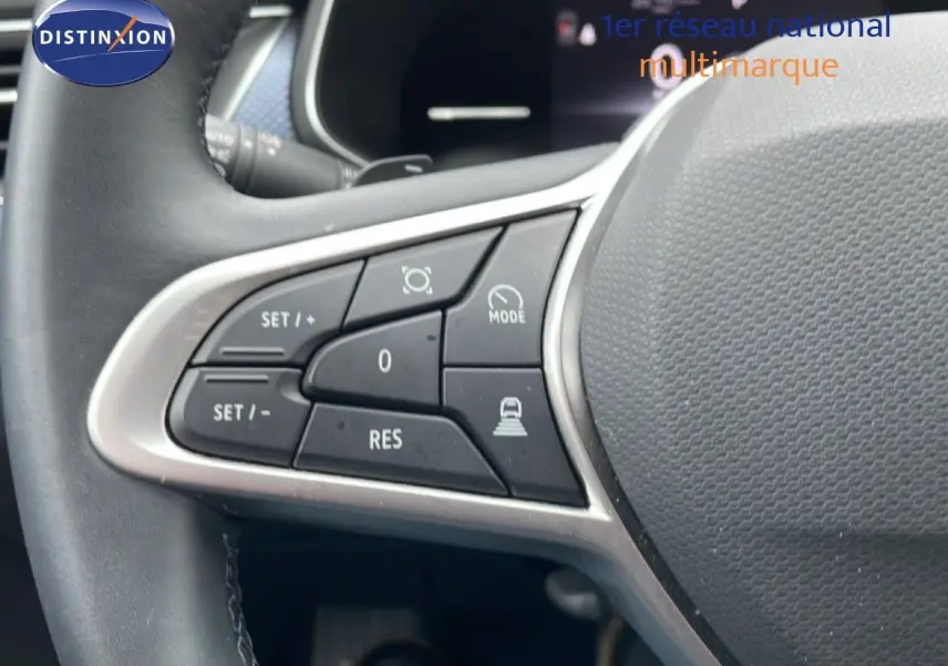 Gros plan sur les commandes de régulateur de vitesse au volant d’un Renault Arkana 2025 bleu Zanzibar métal.