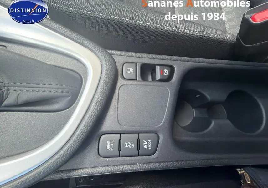 Gros plan sur la console centrale noire de la Toyota Yaris Hybrid 2023, montrant les boutons Drive Mode, EV Mode et frein de parking électronique.