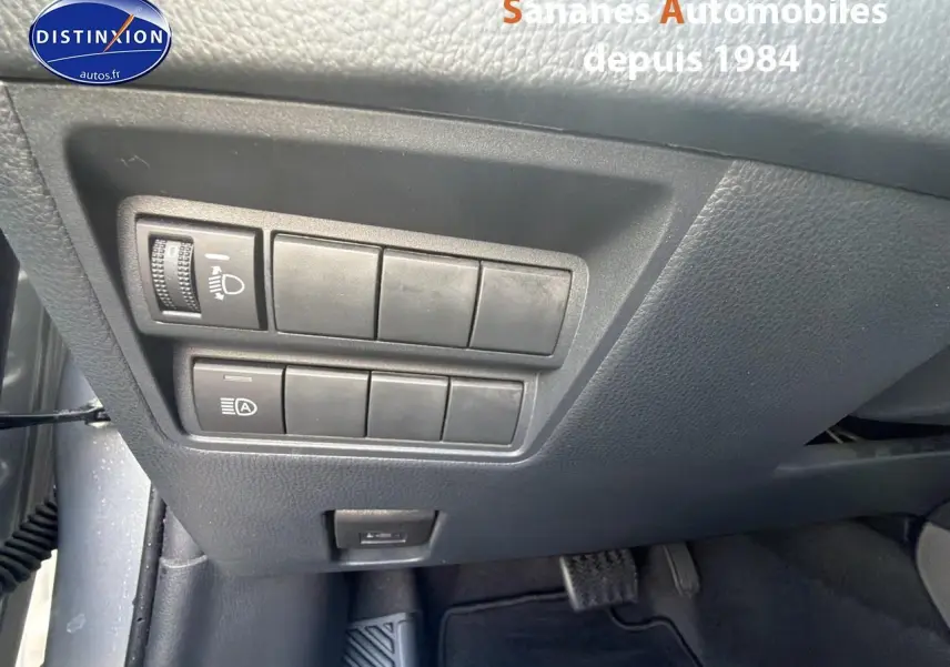 Vue rapprochée des commandes d’éclairage et d’assistance situées sous le tableau de bord côté conducteur de la Toyota Yaris Hybrid 2023 gris métallisé.