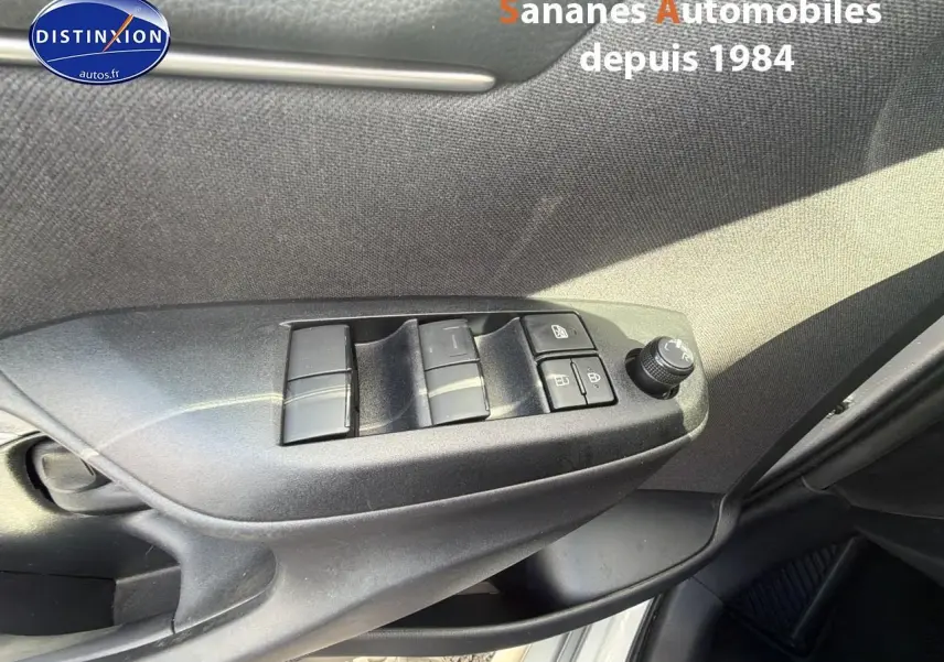 Vue rapprochée des commandes des vitres et rétroviseurs côté conducteur d'une Toyota Yaris Hybrid 2023 en peinture métallisée gris clair.