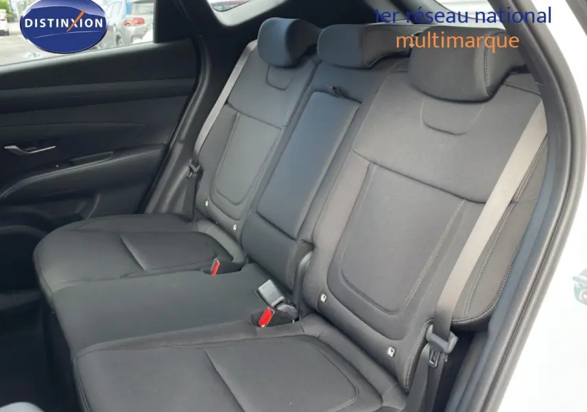 Vue intérieure des sièges arrière en tissu noir du Hyundai Tucson blanc Atlas, avec ceintures de sécurité visibles côté droit.