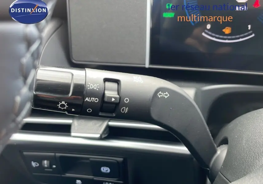 Gros plan sur le commodo gauche du tableau de bord du Hyundai Tucson blanc, avec affichage digital partiel en arrière-plan.