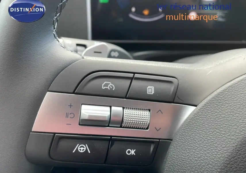 Gros plan sur les commandes au volant à gauche du Hyundai Tucson blanc Atlas, avec molette et boutons multifonctions.
