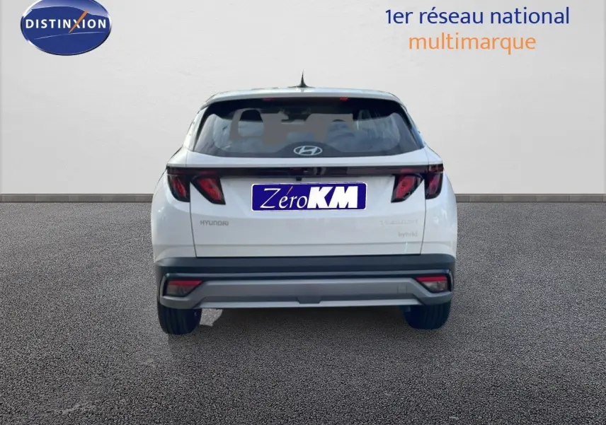 Vue arrière d'un Hyundai Tucson blanc Atlas 2026 avec feux arrière sombres et logo Hyundai visible.
