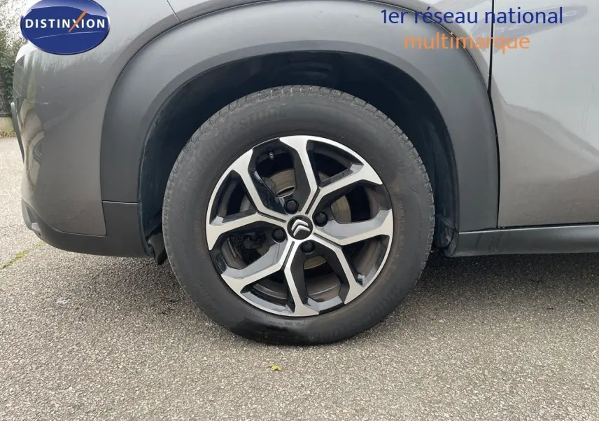 Gros plan sur la roue avant gauche d'un Citroën C3 Aircross gris platinium métal avec jante alliage bicolore.