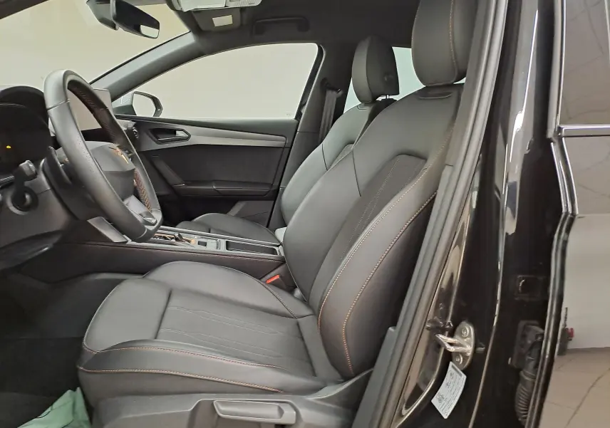 Intérieur côté conducteur de la CUPRA Leon 2025 noir minuit, sièges cuir avec surpiqûres cuivrées et volant multifonction.