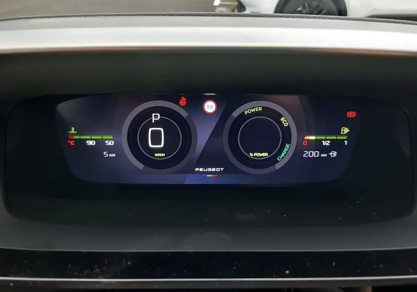 Tableau de bord numérique du Peugeot 308 hybride, affichant la vitesse à 0 km/h et l'autonomie restante.