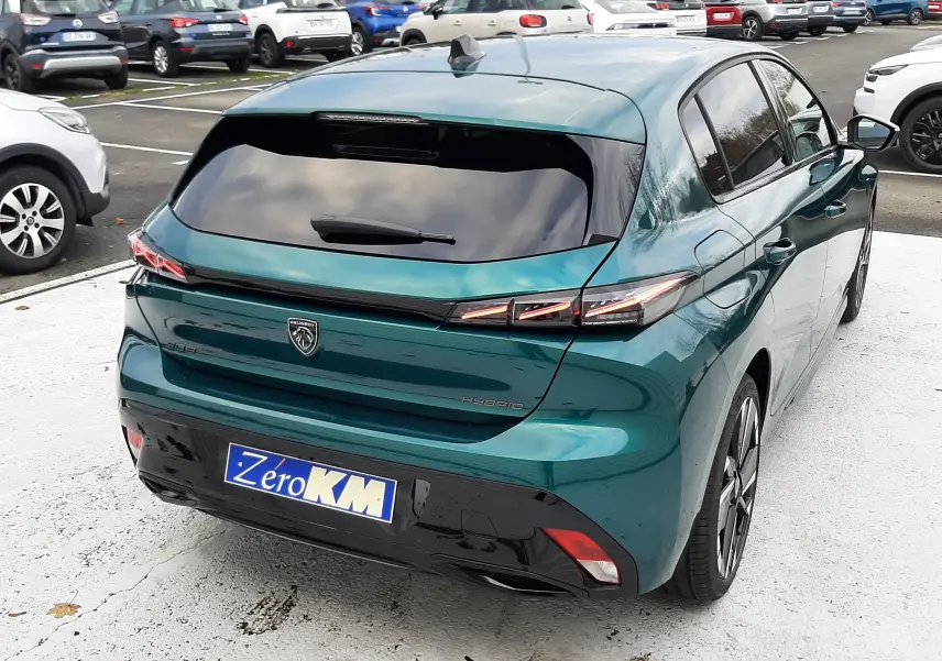 Vue 3/4 arrière droite d'une Peugeot 308 1.2 Hybrid 145ch GT bleu Lagoa avec vitres teintées et feux LED distinctifs.