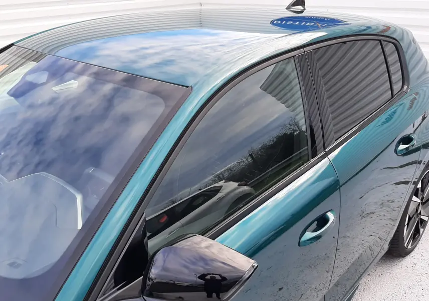 Vue de profil côté gauche sur la Peugeot 308 1.2 Hybrid 145ch GT bleu Lagoa avec rétroviseur noir brillant et vitres teintées.