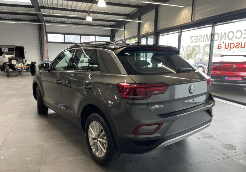 Volkswagen T-Roc gris Indium vu en 3/4 arrière droit avec toit noir et jantes alliage 16 pouces en showroom.