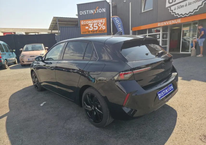 Vue 3/4 arrière droite de l'Opel Astra Hybrid noire avec jantes alliage noires et vitres surteintées.