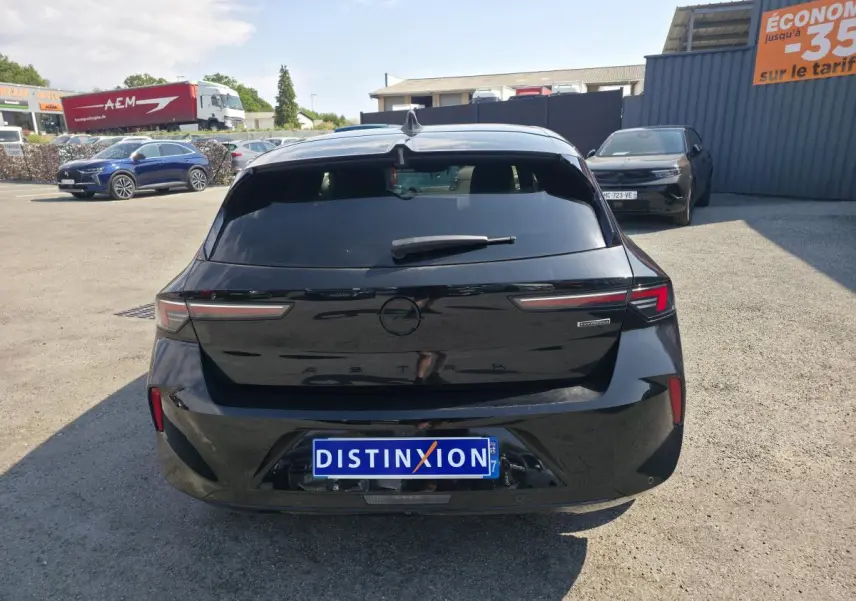 Vue arrière d'une Opel Astra Hybrid noire avec feux LED fins et logo Opel noir sur un parking extérieur.