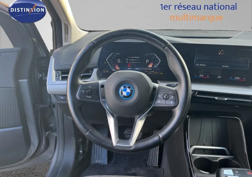 Vue intérieure centrée sur le volant cuir noir et le tableau de bord digital d'une BMW Série 2 Active Tourer 225e XDrive 2022.