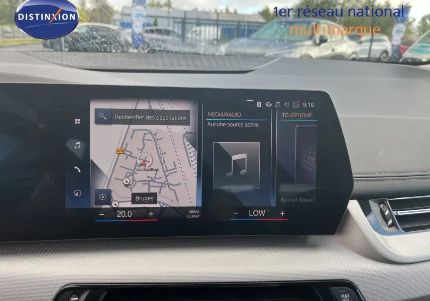 Vue intérieure du tableau de bord de la BMW Série 2 Active Tourer 225e XDrive avec écran tactile affichant la navigation et la climatisation.