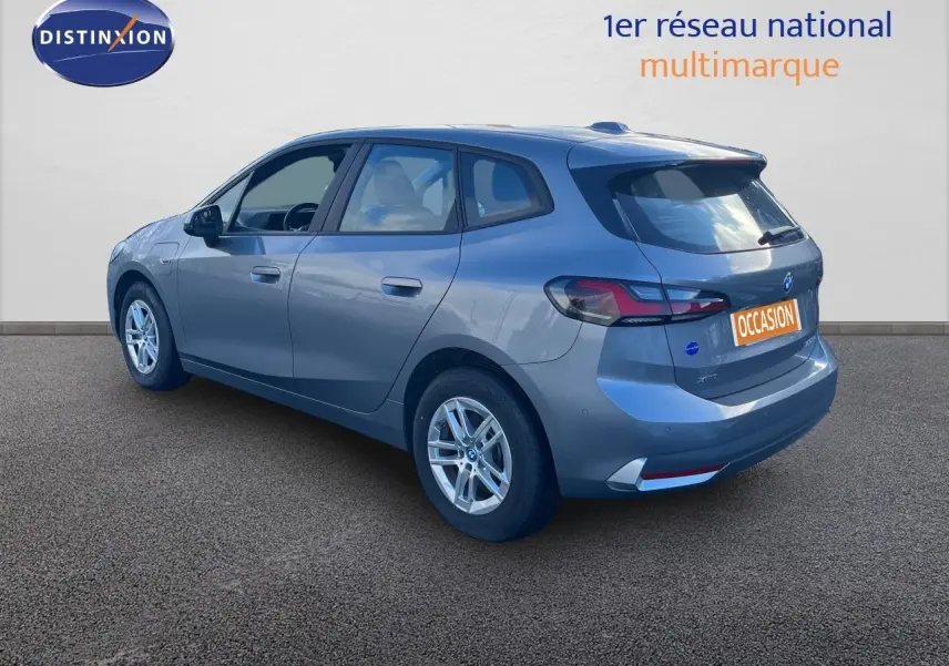 Vue 3/4 arrière droite d'une BMW Série 2 Active Tourer 225e xDrive grise métallisée avec jantes alliage et logo occasion.