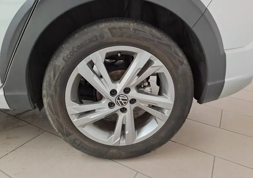 Gros plan sur la roue avant gauche du Volkswagen Taigo 2024 en peinture métallisée Reflet d'argent avec jante alliage R-Line.